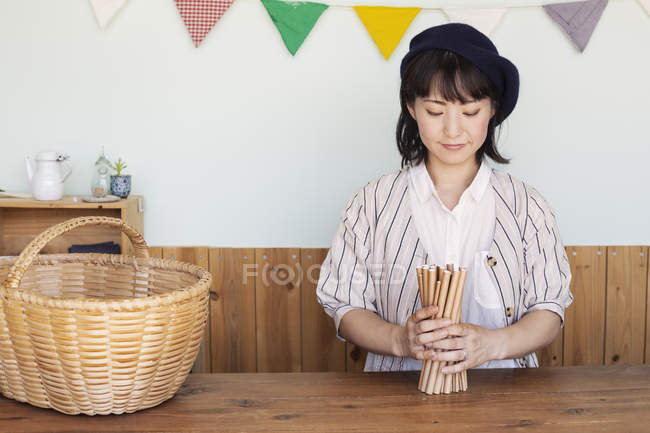 Mujer japonesa de pie junto a una cesta detrás del mostrador en una tienda de granja . - foto de stock
