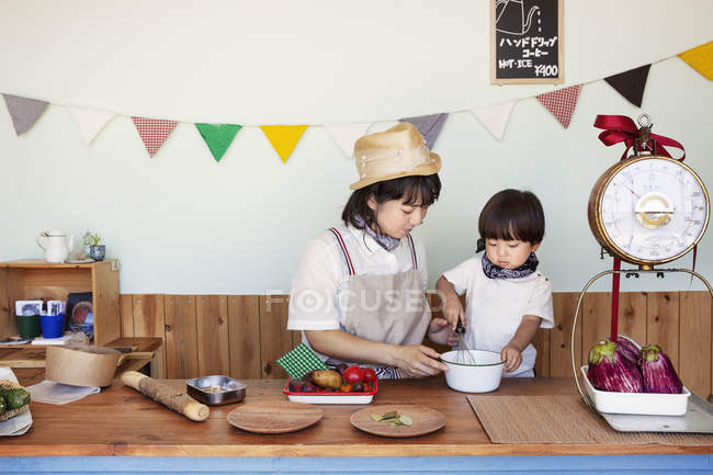 Giapponese donna e ragazzo in piedi in una fattoria negozio, preparare il cibo . — Foto stock