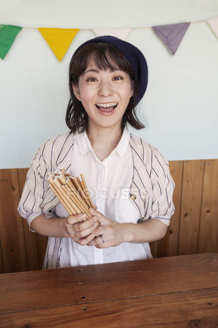 Japanese woman standing behind counter in a farm shop, smiling in camera. — Stock Photo