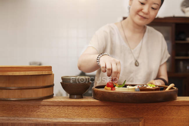 Mujer japonesa preparando verduras frescas en un café vegetariano . - foto de stock