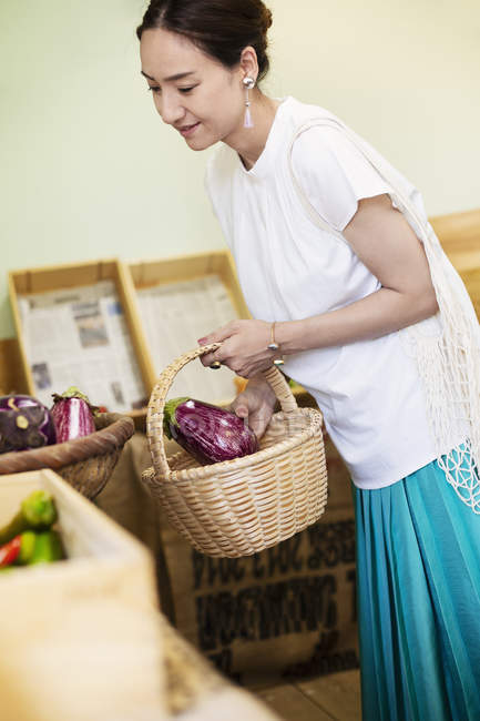 Японська жінка купує свіжі овочі в фермерському магазині.. — стокове фото
