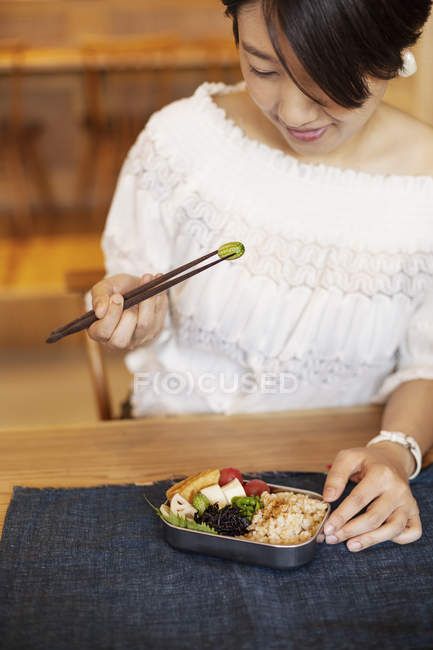 Japanerin isst mit Stäbchen vegetarisch bento in einem Bio-Café. — Stockfoto