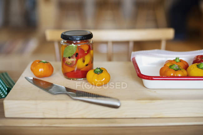 Primer plano de alto ángulo de verduras frescas y conservadas y cuchillo en la tabla de cortar de madera . - foto de stock