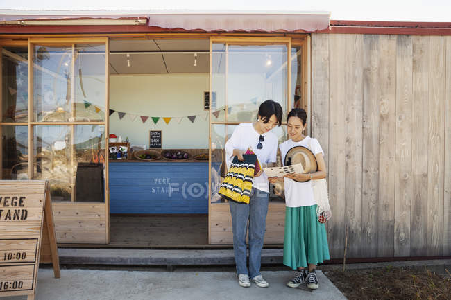 Deux Japonaises souriantes debout devant un magasin de ferme . — Photo de stock