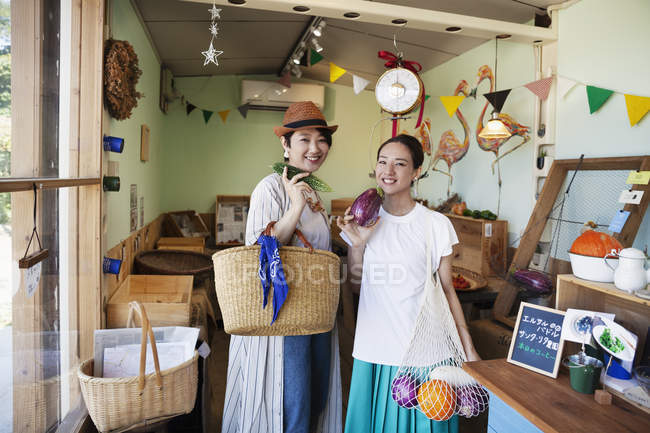 Dos mujeres japonesas sonrientes de pie en una granja, mirando a cámara . - foto de stock