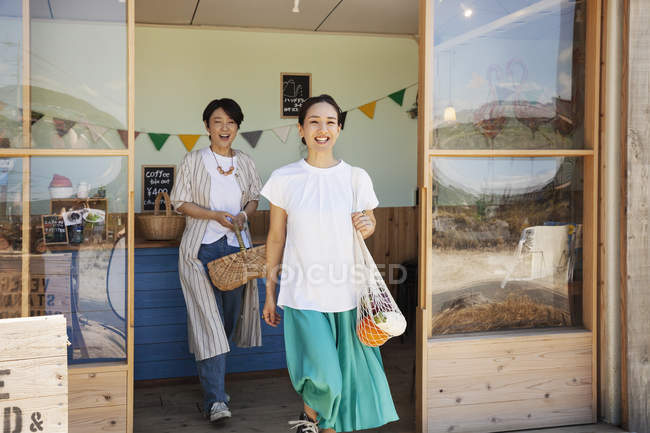 Two smiling Japanese women leaving farm shop. — Stock Photo