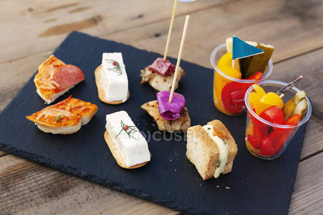 High angle close-up of selection of sandwiches and fresh vegetables on slate tray. — Stock Photo
