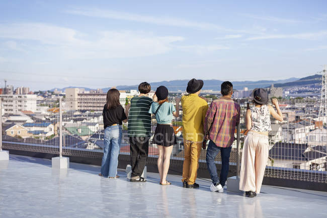 Group of men and women standing on rooftop in urban setting. — Stock Photo