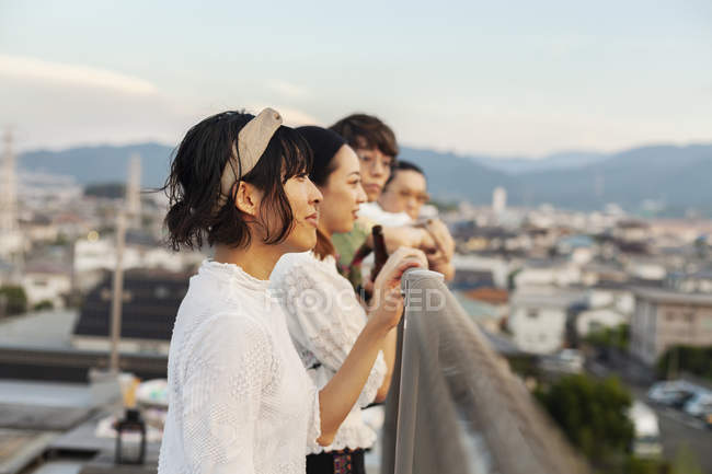 Gruppe junger japanischer Männer und Frauen steht auf einem Dach in urbaner Umgebung. — Stockfoto