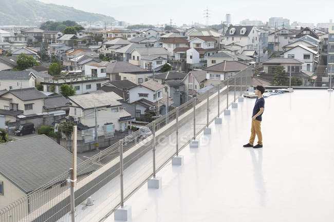 Vue grand angle de l'homme japonais debout sur le toit en milieu urbain . — Photo de stock