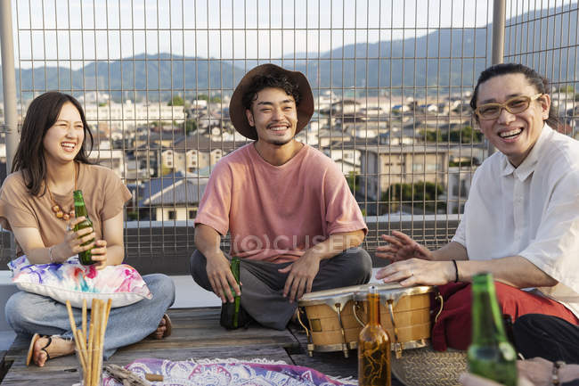 Lächelnde Gruppe junger japanischer Männer und Frauen auf einem Dach in urbaner Umgebung. — Stockfoto