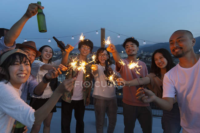 Groupe de jeunes Japonais hommes et femmes avec des étincelles sur le toit en milieu urbain . — Photo de stock
