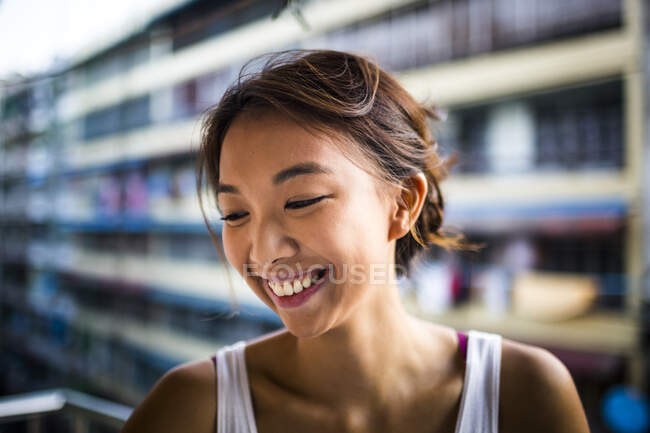 Portrait of smiling young woman with brown hair standing on a balcony. — Stock Photo