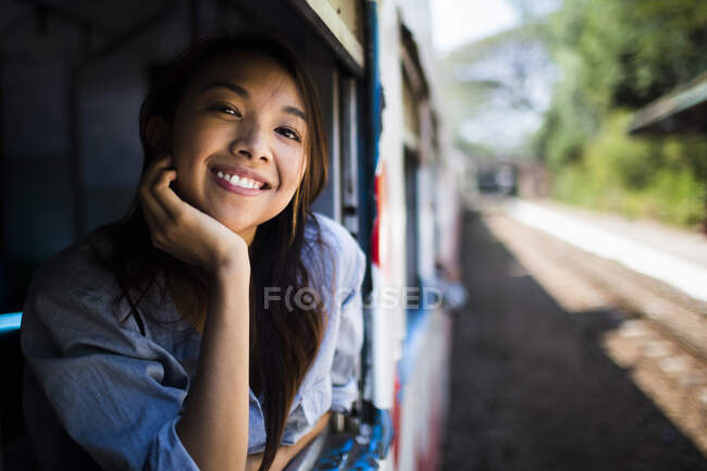 Усміхнена молода жінка їде на поїзді, дивлячись з вікна . — стокове фото