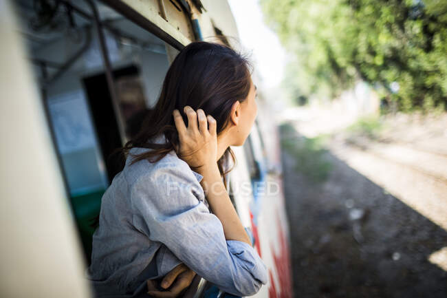 Mujer joven que conduce en tren, mirando fuera de la ventana. - foto de stock