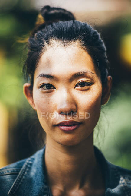 Retrato de uma jovem com cabelo preto amarrado em um nó superior, olhando para a câmera. — Fotografia de Stock