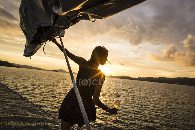 Mujer portadora de vino a bordo de un barco, crucero para cenar al atardecer en el Océano Índico.. - foto de stock