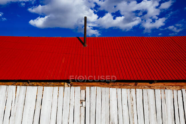 Ângulo baixo perto do edifício de madeira branco com telhado vermelho brilhante sob um céu nublado
. — Fotografia de Stock
