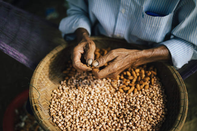 High angle close-up of man shelling peanuts on street. — Stock Photo