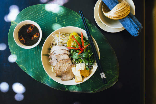 Alto ângulo close-up de tigela de macarrão Cao Lau com porco grelhado e ervas . — Fotografia de Stock