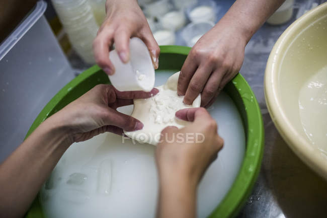 Primer plano de la fabricación de queso, gente vertiendo crema y cuajada en el bolso de burrata . - foto de stock