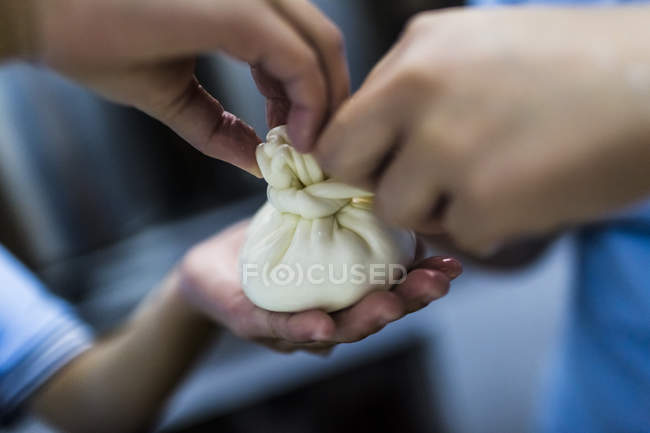 Close-up of cheese-making, people tying cream and curd into burrata purse. — Stock Photo