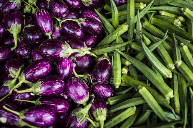 Primer plano de alto ángulo de las berenjenas y hortalizas de okra en el mercado . - foto de stock