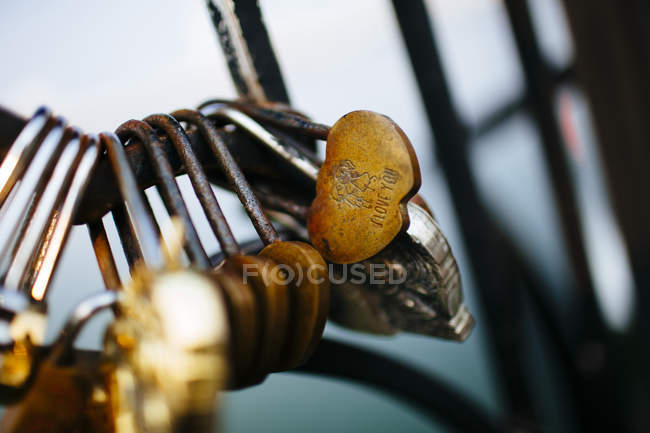 Close-up of locks of love on bridge railing with selective focus. — Stock Photo
