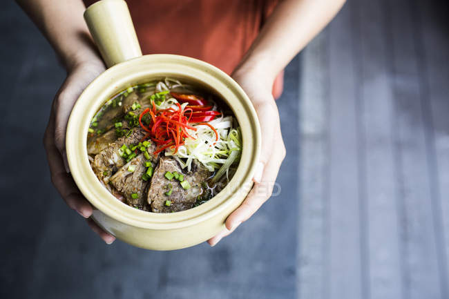 High angle close-up of person holding bowl of Bun Bo Hue. — Stock Photo