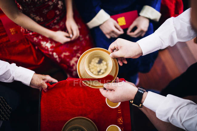 High angle close-up of a ritual at Chinese wedding ceremony, people passing a bowl of soup. — Stock Photo