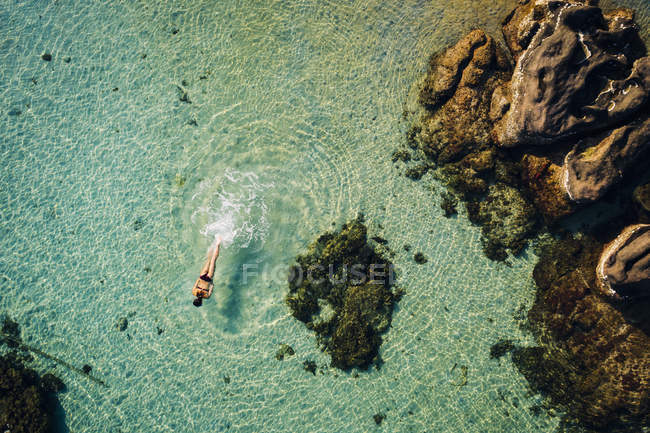 Високий кут зору жінки, що плаває в океанічній воді між каменями, Фу Куок, В'єтнам — стокове фото