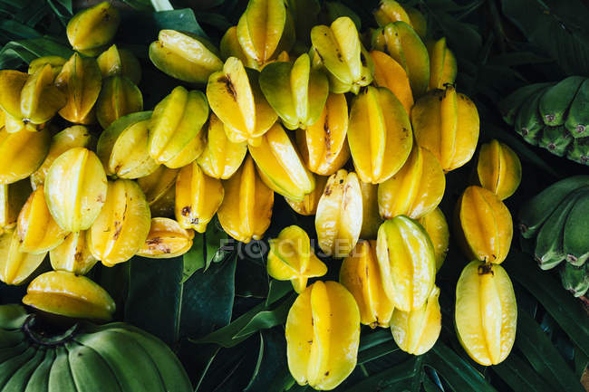 Close-up of star fruits and green bananas for sale along side of road. — Stock Photo