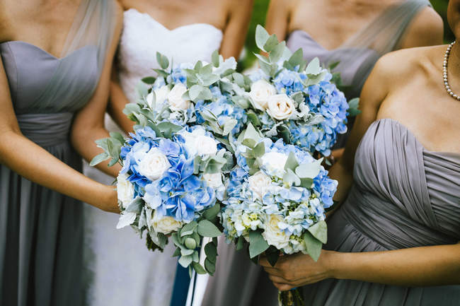 Vista de ángulo alto de novia y damas de honor con ramos de flores azules y blancas . - foto de stock