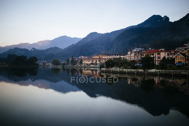 Buildings and mountains reflected in small lake, Vietnam. — Stock Photo