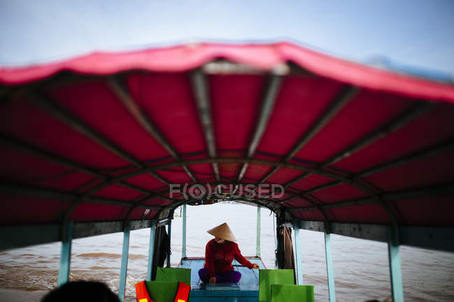 Woman piloting a boat with red canopy through a river in Mekong Delta, Vietnam. — Stock Photo