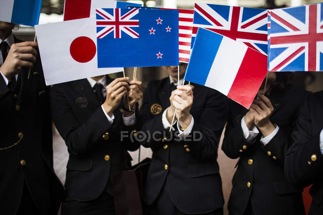 Close-up of people in uniform waving small national flags, Nagasaki, Kyushu, Japan — Stock Photo