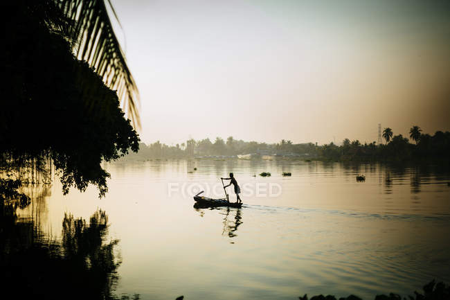 Місцевий рибалка веслує човен на річці рано - вранці (В 