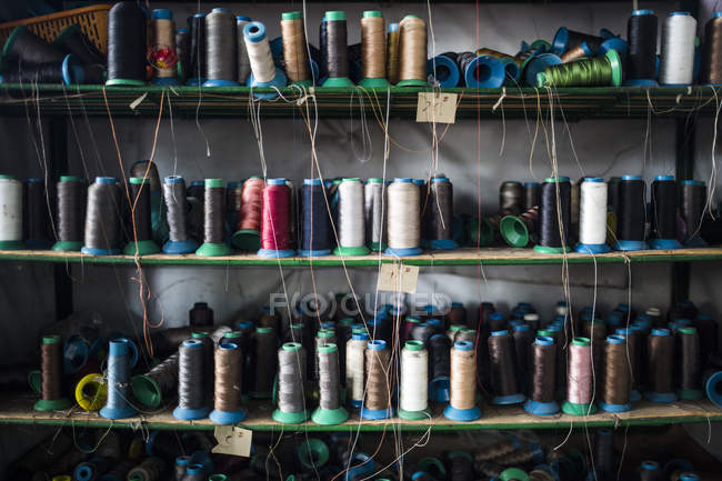Primer plano de estantes de hilos de colores para coser suelas de zapatos en fábrica, Binh Duong, Vietnam - foto de stock
