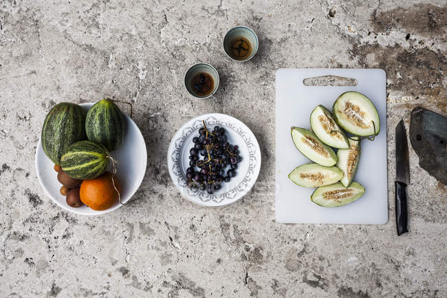 Primo piano ad angolo alto del tavolo in pietra con tè e selezione di frutta fresca su piatti e tagliere . — Foto stock