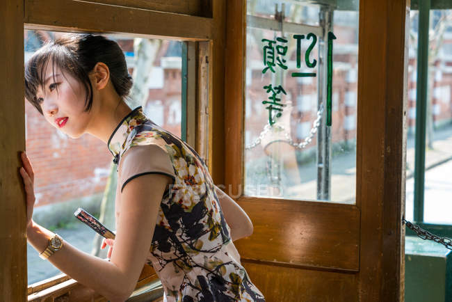 Local young Chinese woman in vintage Asian dress in old retro tram, Shanghai, China — Stock Photo