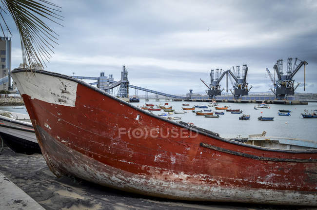 Красная старая лодка с обшарпанным корпусом на берегу у воды в Лисбоне, Португалия — стоковое фото