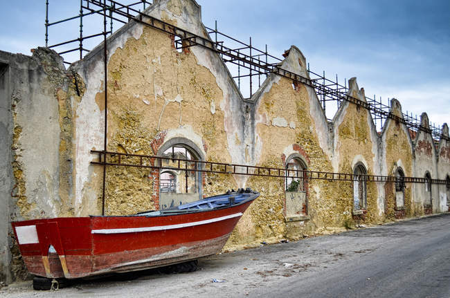 Barco rojo tirado en la calle alineado con el edificio en ruinas, Lisboa, Portugal . - foto de stock