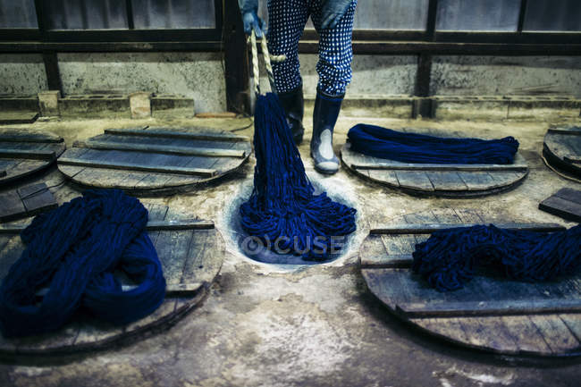 Primo piano dell'uomo che picchia il colorante indaco in fili di cotone . — Foto stock