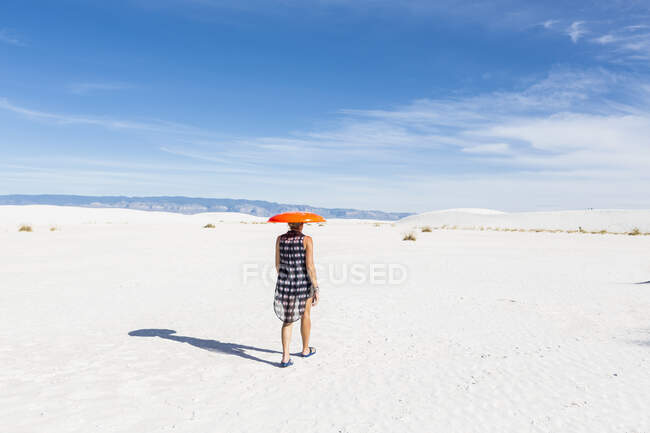 Frau trägt orangefarbenen Schlitten auf dem Kopf, White Sands National Monument, NM — Stockfoto