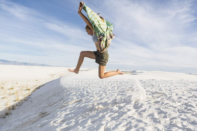 Athletic 13 year old girl leaping in the sand, White Sands Nat'l Monument, NM — Stock Photo