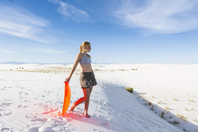 Девочка-подросток с санками на вершине подъема у монумента Белые пески, шт. Нью-Мексико — стоковое фото