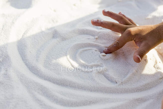 Jeune garçon dessinant à la main dans le sable, grenaille coupée — Photo de stock