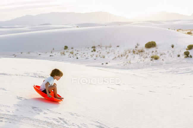 6 anno vecchio ragazzo slittino giù dune, Bianco sabbie Na'l Monumento, NM — Foto stock