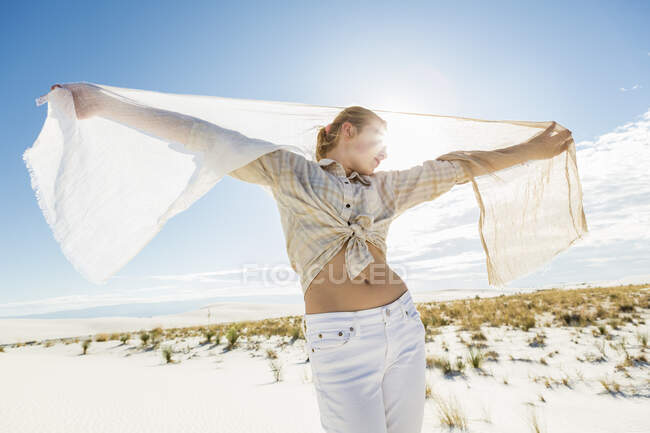 13 year old girl dancing with a shawl in the open space of white sand dunes. — Stock Photo