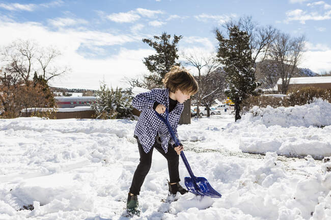 Sei anni ragazzo pala neve in vialetto — Foto stock